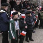 dzieci stojące w rzędzie i trzymające polskie flagi