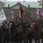 obchody 11 listopada - na pierwszym planie żołnierze na koniach, ulica przybrana w flagi narodowe