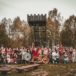 zdjęcie z Wiecu Piastowskiego w Grodzie Pobiedziska, grupa ludzi pozuje do zdjęcia w strojach stylizowanych na czasy wczesnośredniowieczne, wyposażeni w tarcze, miecze i flagi