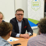 starosta poznański Jan Grabkowski przy stole rozmawiający z komisją konkursową oceniającą pączki