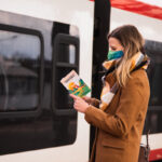 osoba czytająca Przewodnik Niedzielnego Tropiciela wsiadając do pociągu