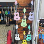 kolorowe ukulele wiszące na drewnianej ściance